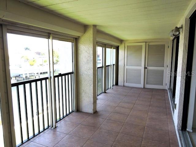A covered balcony features tiled flooring, black railings, and white louvered doors — 1433 MEDITERRANEAN DRIVE UNIT C, PUNTA GORDA, FL