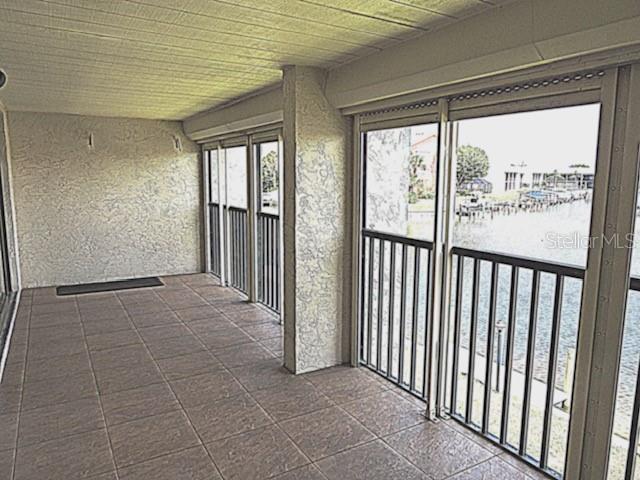 A covered balcony with tiled flooring overlooks a canal through screened-in sliding glass doors — 1433 MEDITERRANEAN DRIVE UNIT C, PUNTA GORDA, FL