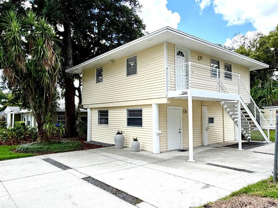 A two-story, light yellow house with an exterior staircase leading to an upper-level balcony — 2568 LOTAFUN AVENUE, WINTER PARK, FL