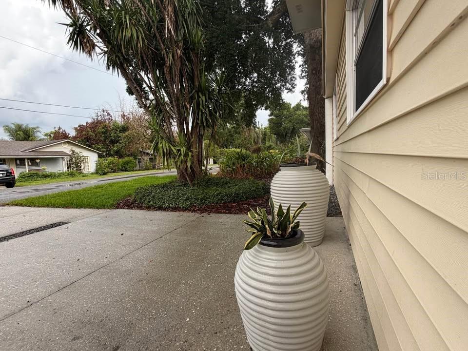 Two large, ribbed, light-colored planters sit on a concrete walkway beside a yellow-sided house — 2568 LOTAFUN AVENUE, WINTER PARK, FL
