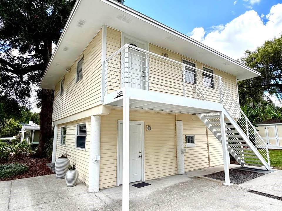 A two-story yellow house with a white metal staircase leading to an upper-level balcony — 2568 LOTAFUN AVENUE, WINTER PARK, FL