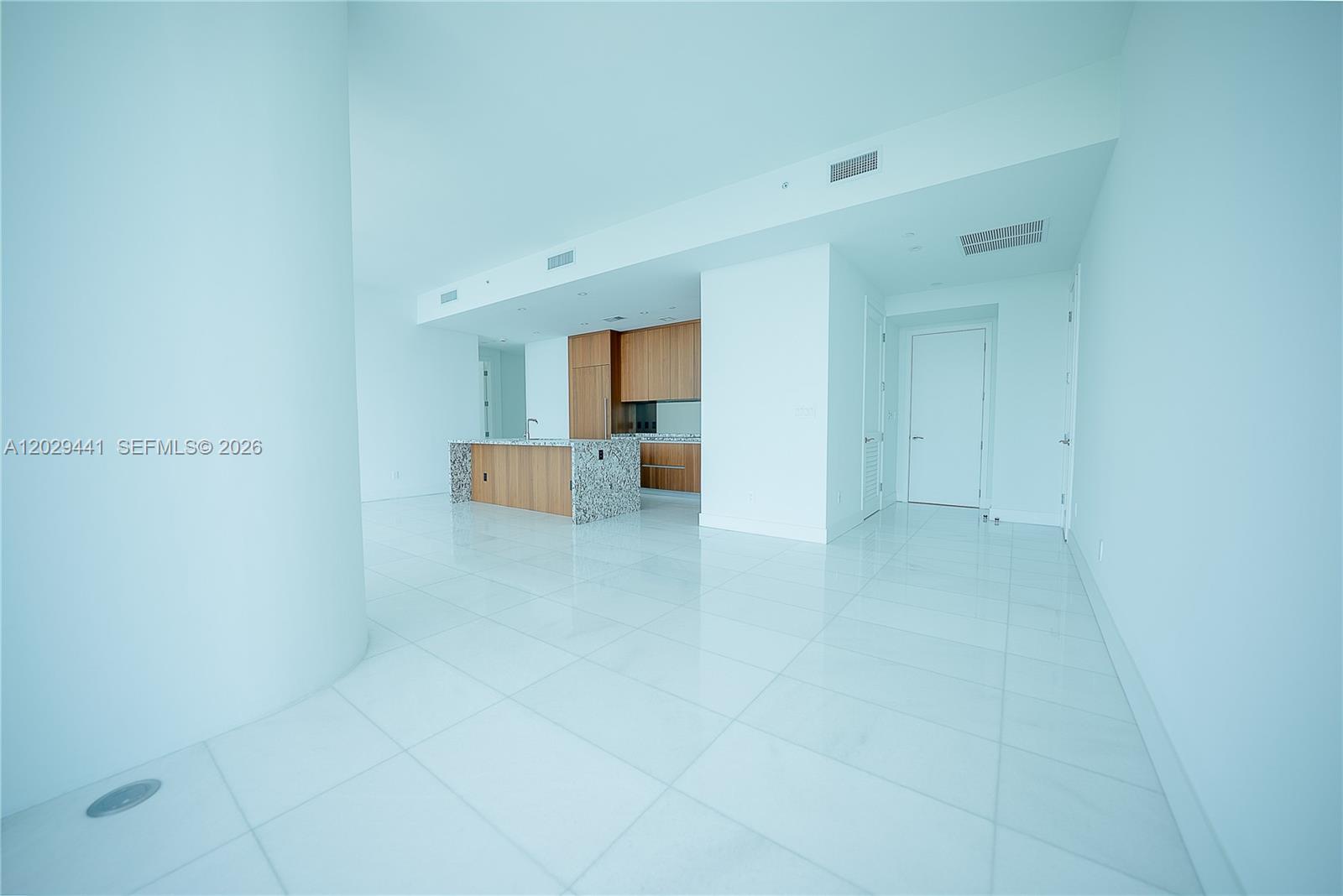 This modern open-concept kitchen features wood cabinetry, a granite island, and white tile flooring — 175 SE 25th Rd # 2103, Miami FL 33129, MIAMI, FL