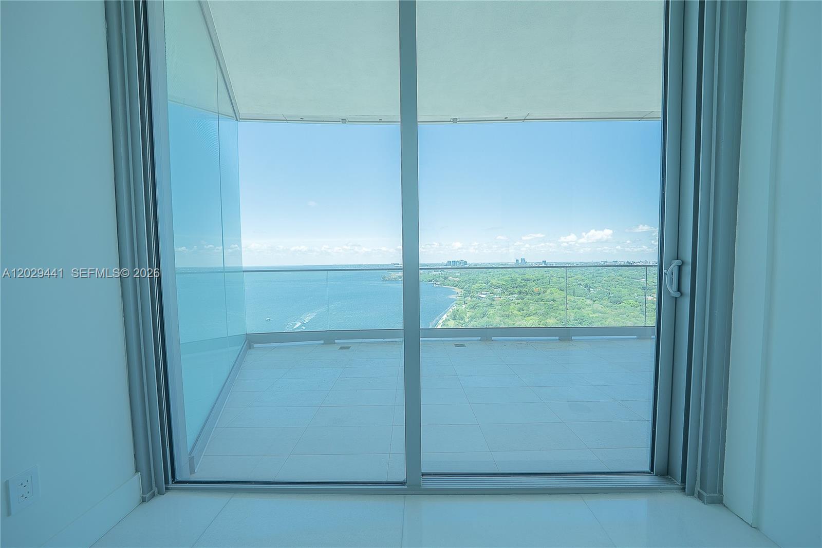 A view of a balcony and the ocean through large sliding glass doors — 175 SE 25th Rd # 2103, Miami FL 33129, MIAMI, FL