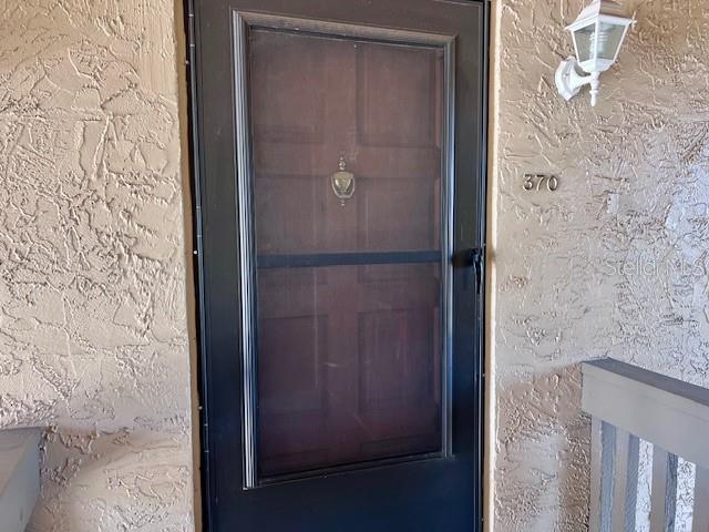 A dark storm door with a brass knocker is mounted on a textured beige wall — 370 WINDMEADOWS STREET UNIT 370, ALTAMONTE SPRINGS, FL