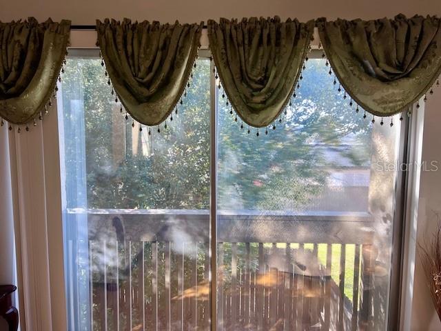 A sliding glass door features green decorative valances with fringe trim and a balcony view — 370 WINDMEADOWS STREET UNIT 370, ALTAMONTE SPRINGS, FL