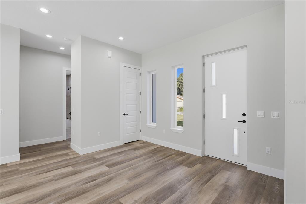 An entryway features light wood-look flooring, white walls, a modern front door, and two narrow windows — 12 PERTHSHIRE LANE, PALM COAST, FL