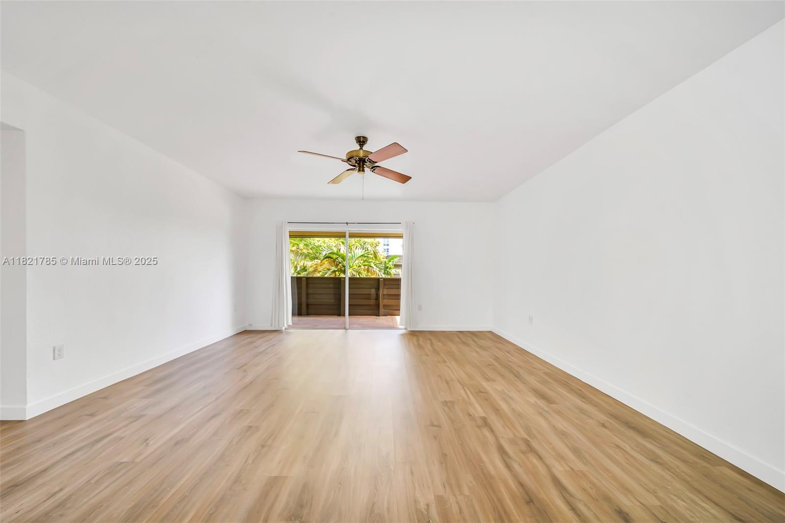 An empty room features white walls, light wood-look flooring, a ceiling fan, and sliding glass doors — 8335 SW 72nd Ave # 315D, Miami FL 33143, MIAMI, FL