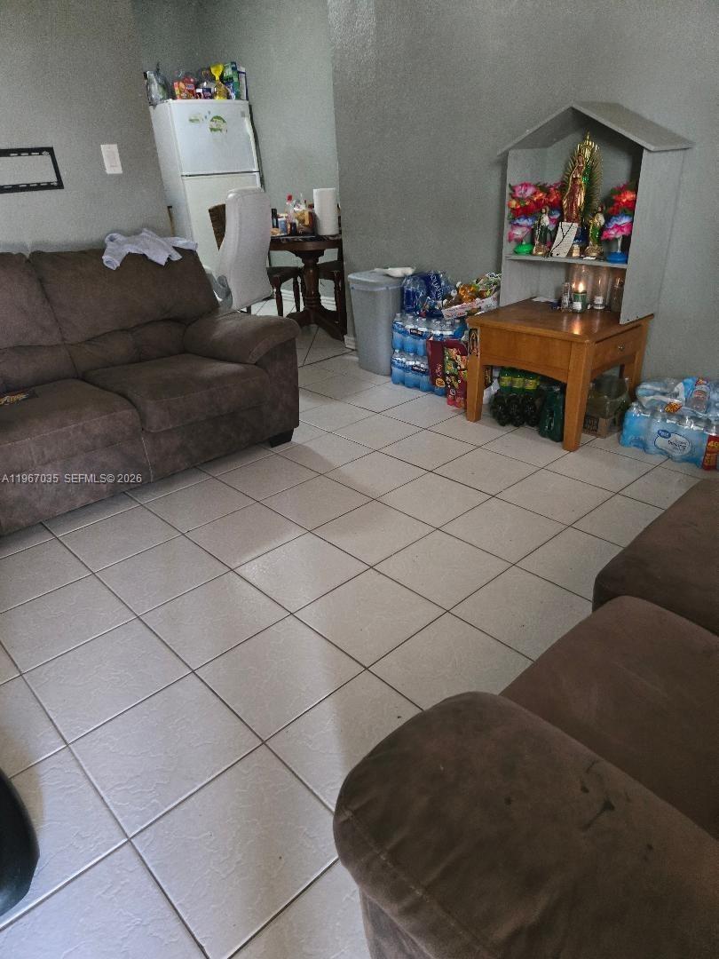 A living room features brown sofas, tiled floors, and a small wooden altar shelf — 2100 NW 4th St, Pompano Beach FL 33069, POMPANO BEACH, FL