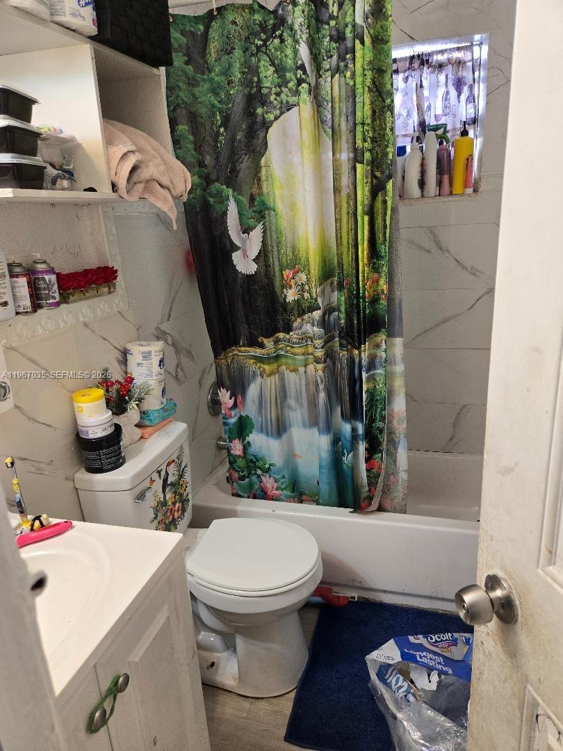 A small bathroom features a white toilet, a vanity, and a shower with a nature-themed curtain — 2100 NW 4th St, Pompano Beach FL 33069, POMPANO BEACH, FL