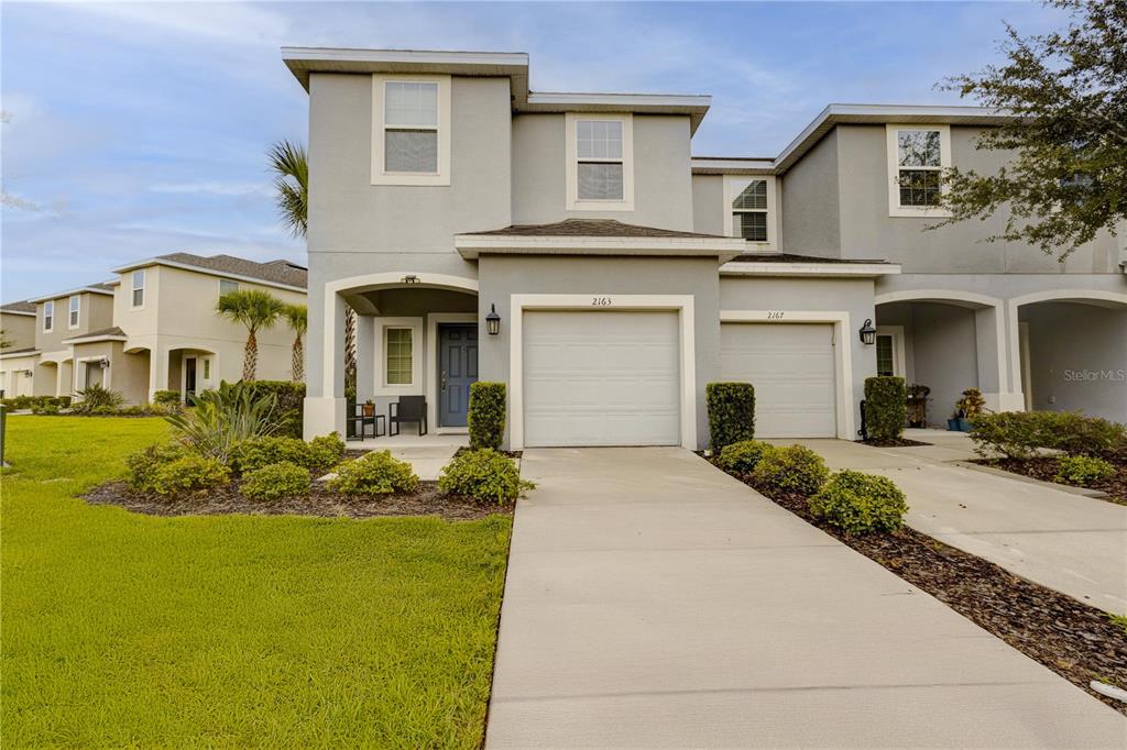 A two-story townhouse with a gray stucco exterior, a one-car garage, and a concrete driveway — 2163 CRYSTAL BELL STREET, ORLANDO, FL