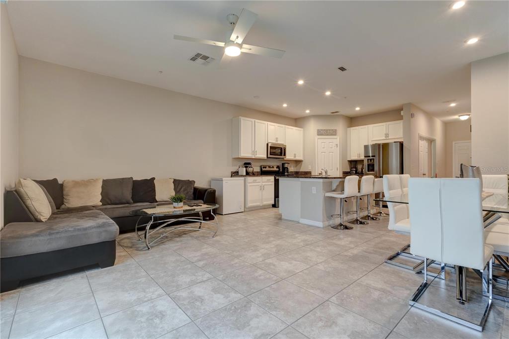 An open-concept living room and kitchen with tile flooring, white cabinets, and a sectional sofa — 2163 CRYSTAL BELL STREET, ORLANDO, FL