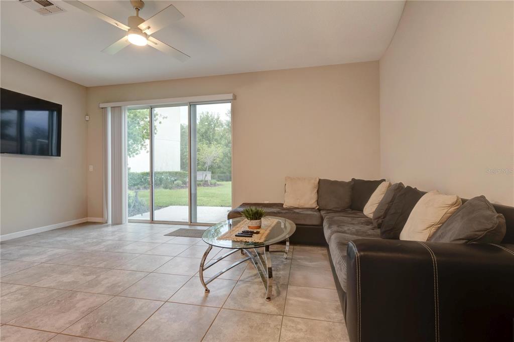 A living room features tile flooring, a sectional sofa, a glass coffee table, and sliding doors — 2163 CRYSTAL BELL STREET, ORLANDO, FL