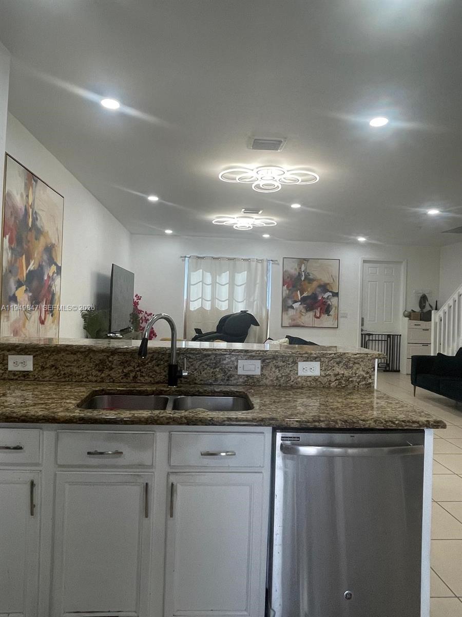 A kitchen island with a granite countertop and stainless steel sink overlooks a living area — 9421 SW 171st Pl, Miami FL 33196, MIAMI, FL