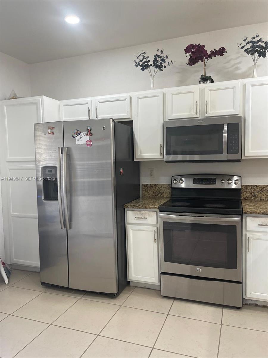 A kitchen features white cabinets, stainless steel appliances, and speckled granite countertops — 9421 SW 171st Pl, Miami FL 33196, MIAMI, FL