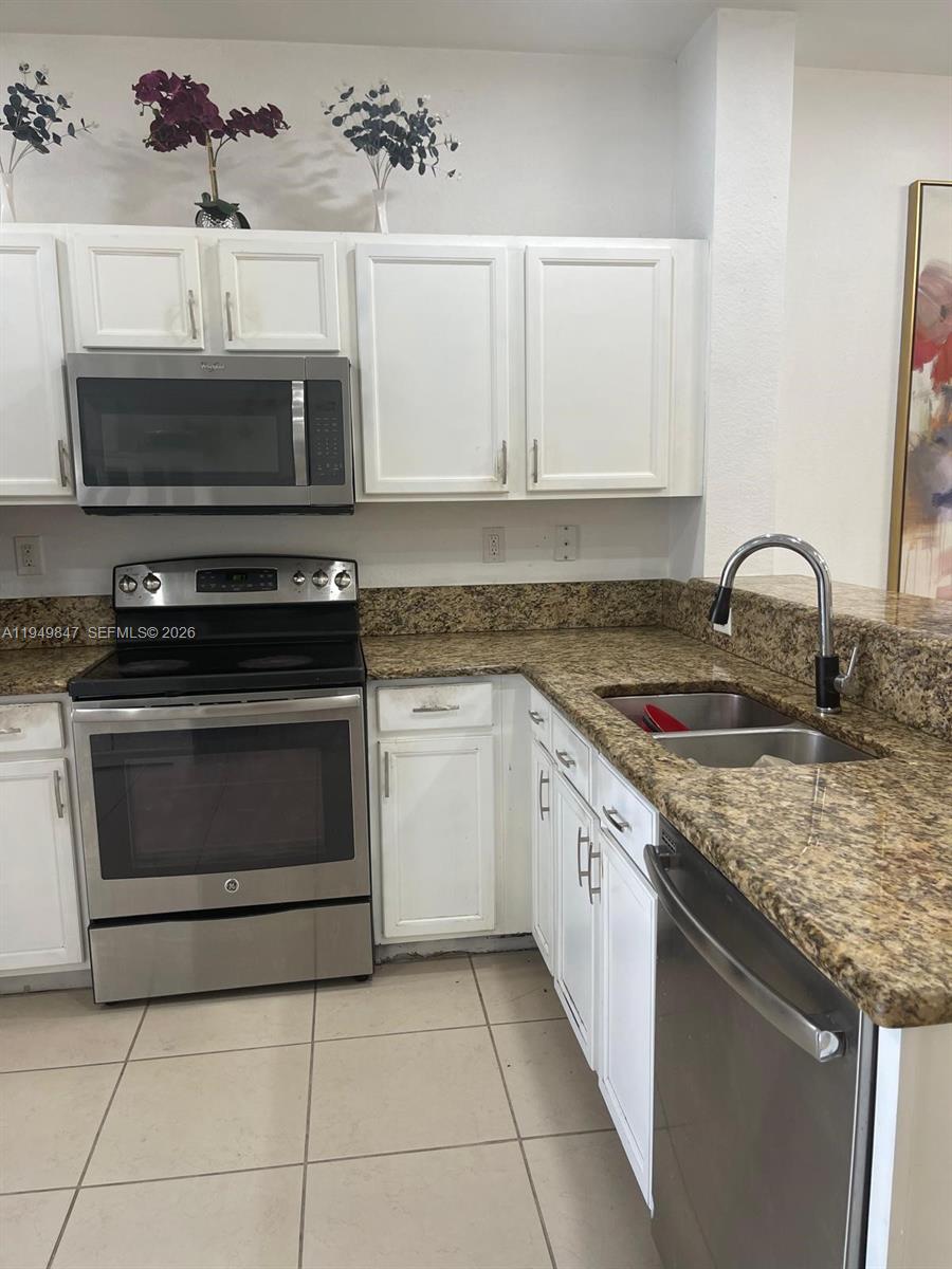 A kitchen features white cabinets, stainless steel appliances, and speckled granite countertops — 9421 SW 171st Pl, Miami FL 33196, MIAMI, FL