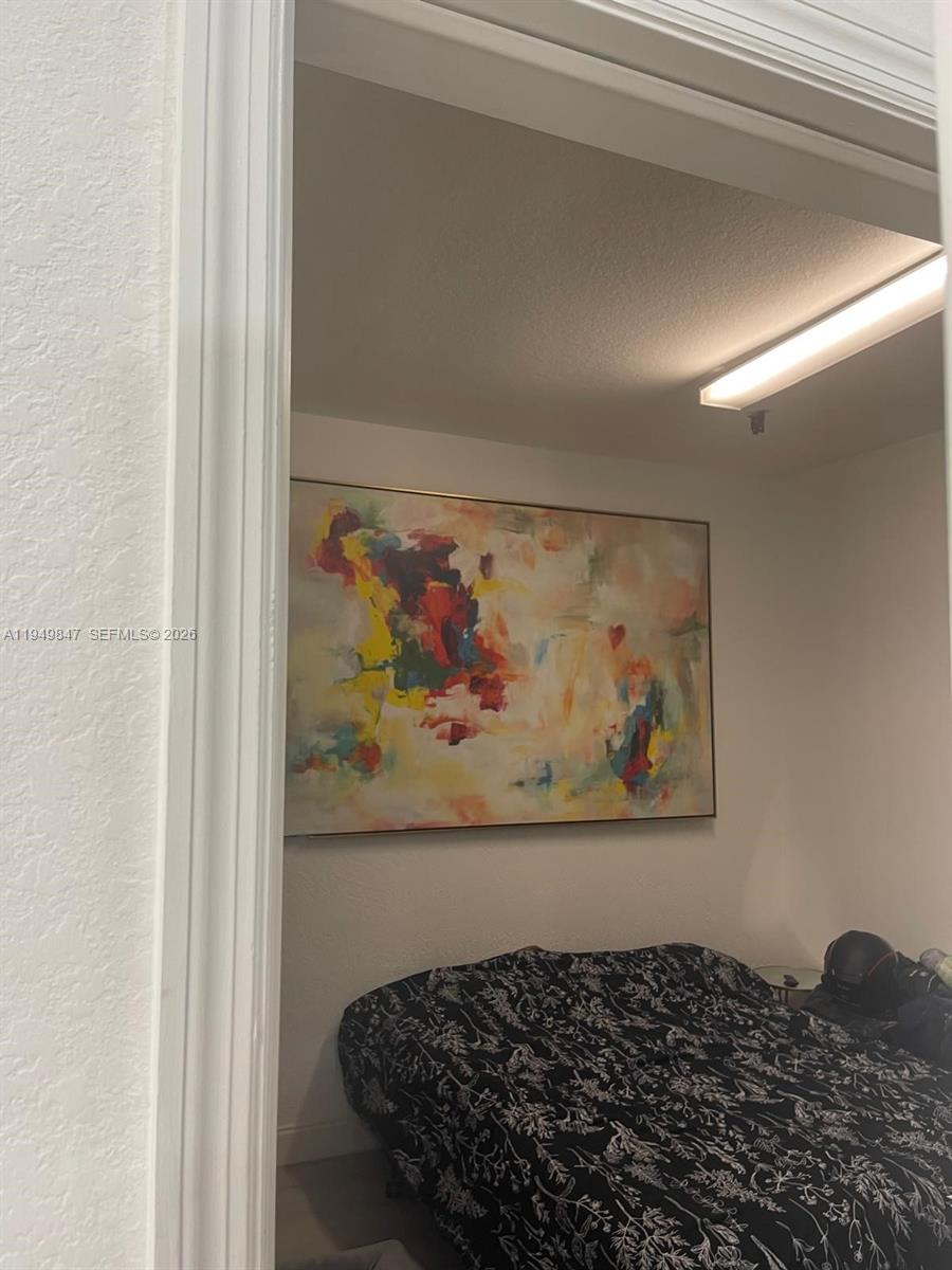 A bedroom features a large abstract painting hanging above a bed with a patterned comforter — 9421 SW 171st Pl, Miami FL 33196, MIAMI, FL