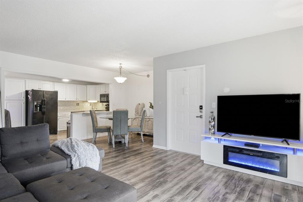 A living room with gray flooring, a sectional sofa, and a white media console fireplace — 1179 PINE RIDGE CIRCLE W UNIT G1, TARPON SPRINGS, FL