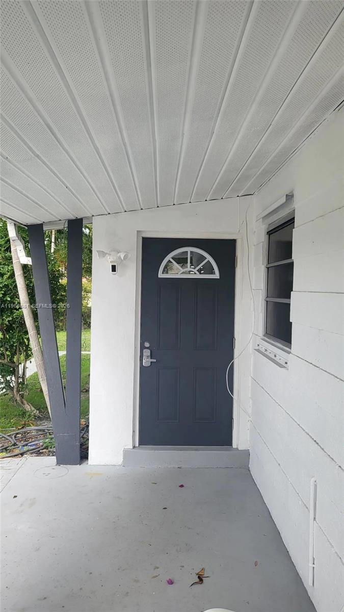 A covered porch features a dark gray front door and a white exterior wall — 821 NE 6th St # 1, Hallandale Beach FL 33009, HALLANDALE BEACH, FL