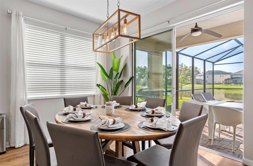 A dining room with a round wooden table, modern light fixture, and sliding glass doors — 4443 SHIVA LOOP, KISSIMMEE, FL