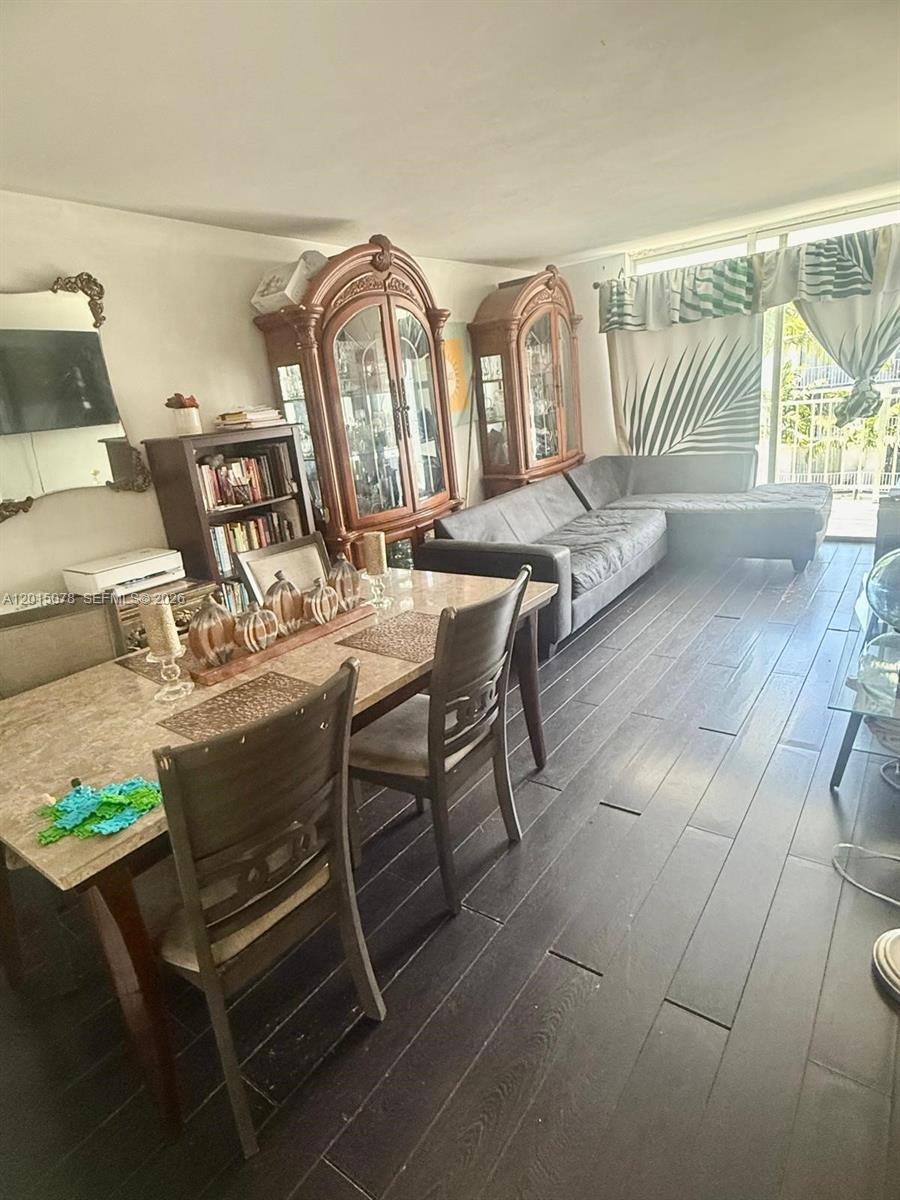 A dining area and living room feature dark wood floors, a sectional sofa, and cabinets — 488 NW 165th St Rd # 512, Miami FL 33169, MIAMI, FL