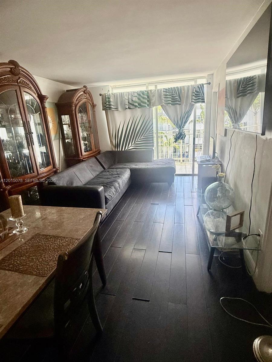 A living room features dark wood flooring, a sectional sofa, and two ornate wooden cabinets — 488 NW 165th St Rd # 512, Miami FL 33169, MIAMI, FL