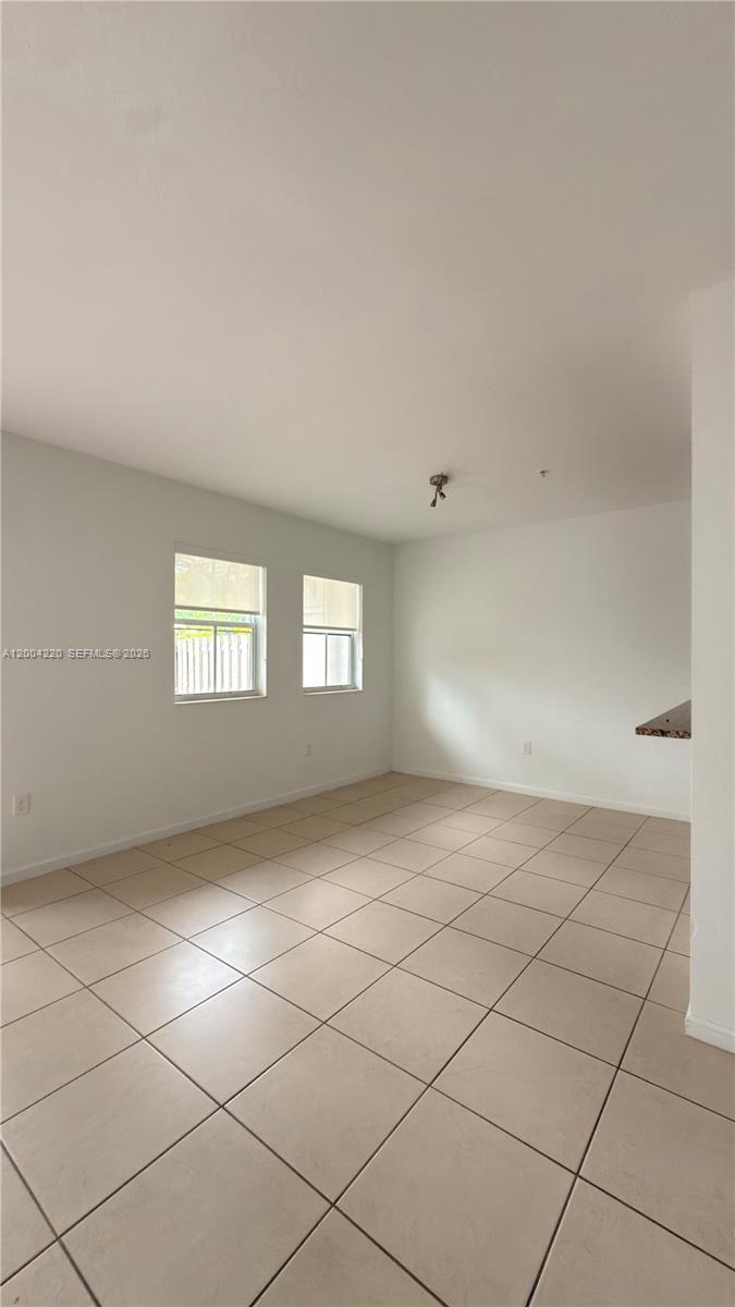 An empty room features white walls, beige tile flooring, and two windows — 8900 NW 97th Ave # 104, Doral FL 33178, DORAL, FL
