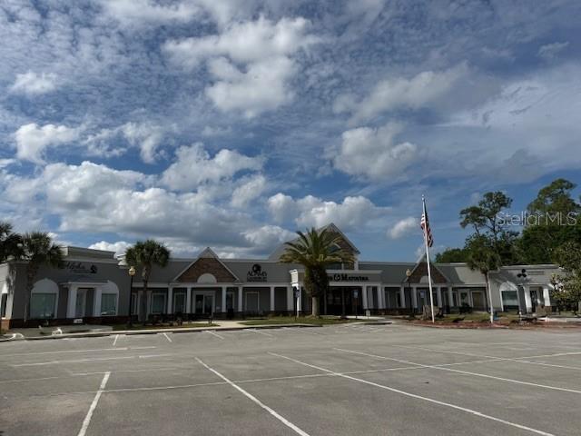 A low-rise commercial building with a parking lot under a cloudy blue sky — 20 AIRPORT ROAD UNIT D&E, PALM COAST, FL