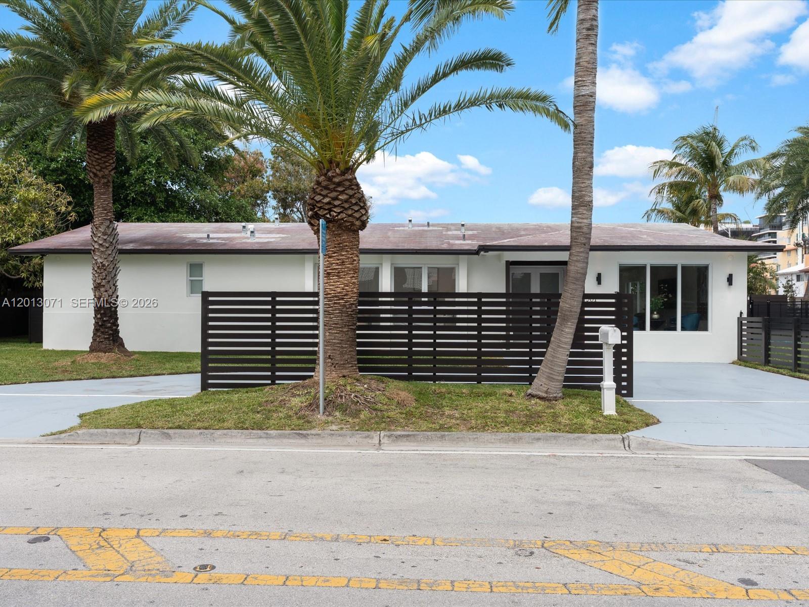 A single-story white house features a dark horizontal slat fence and two palm trees — 301 88th St, Surfside FL 33154, SURFSIDE, FL