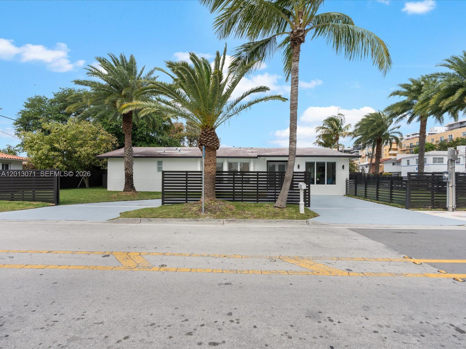 A single-story white house features a black horizontal fence and several palm trees — 301 88th St, Surfside FL 33154, SURFSIDE, FL