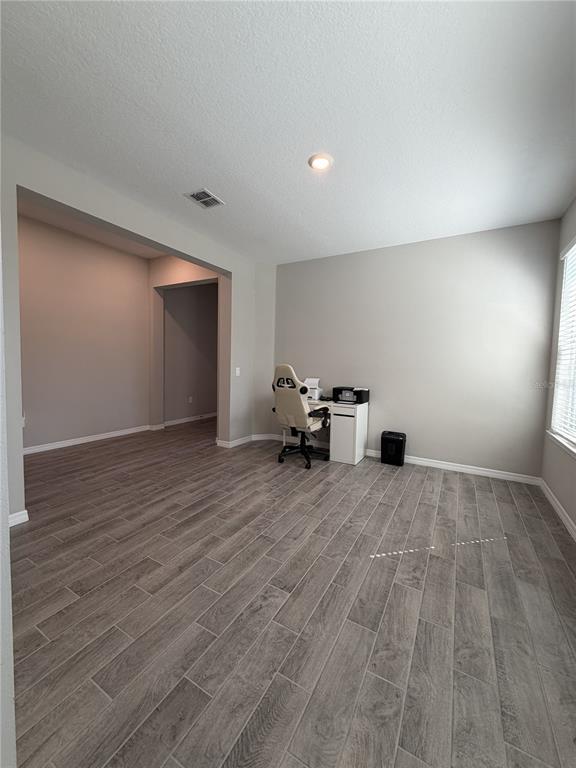 A room with gray wood-look tile flooring, light gray walls, and a small white desk — 3818 ROSE MALLOW DRIVE, KISSIMMEE, FL