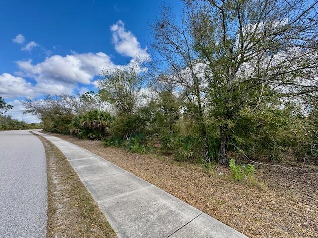 A paved sidewalk runs alongside a wooded area under a blue sky with clouds — 4921 S Fairway Drive, Punta Gorda FL 33982, PUNTA GORDA, FL