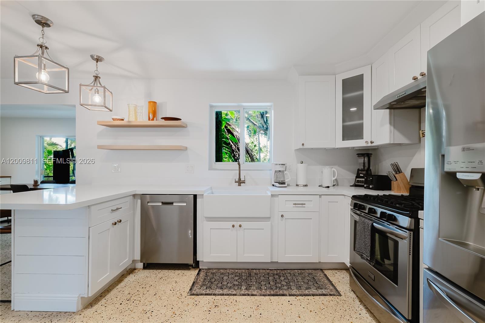 A bright kitchen features white cabinets, stainless steel appliances, a farmhouse sink, and terrazzo flooring — 1106 N 13th Ct, Hollywood FL 33019, HOLLYWOOD, FL