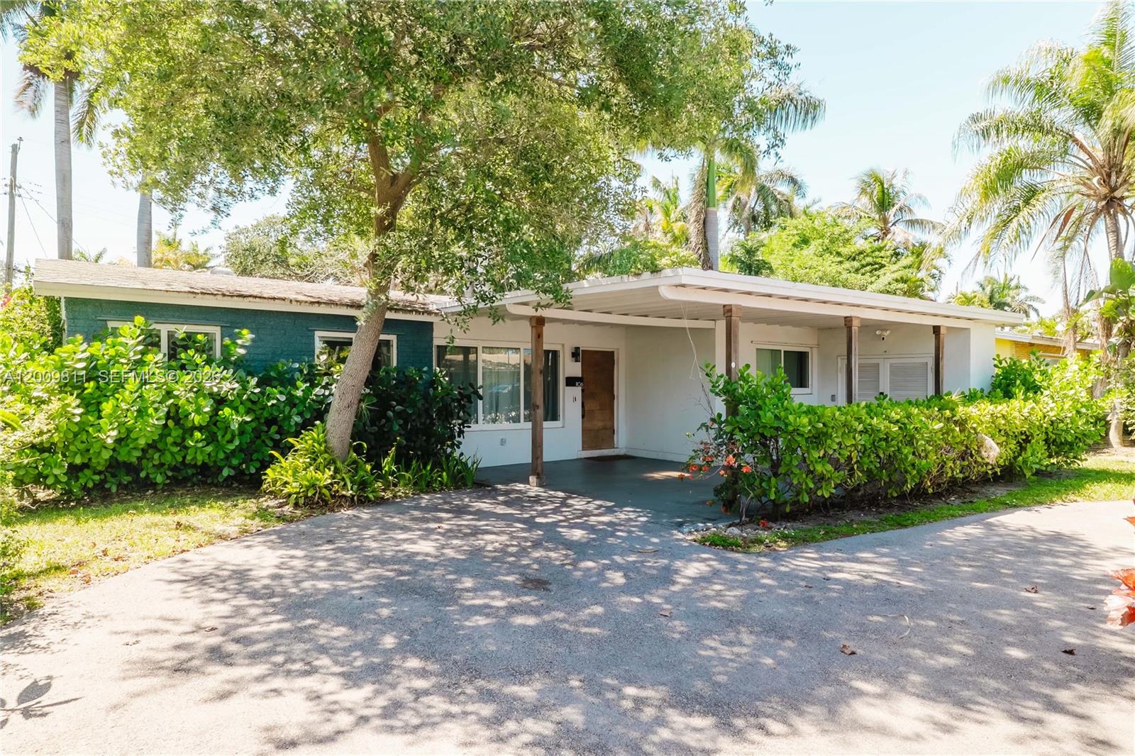 A single-story house with a blue brick facade, a carport, and lush landscaping — 1106 N 13th Ct, Hollywood FL 33019, HOLLYWOOD, FL