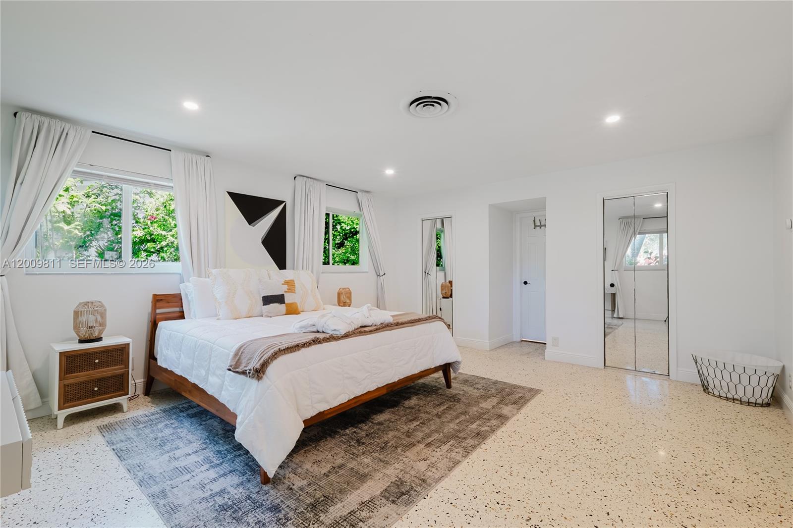A bedroom features a wooden bed, a patterned area rug, and light-colored terrazzo flooring — 1106 N 13th Ct, Hollywood FL 33019, HOLLYWOOD, FL