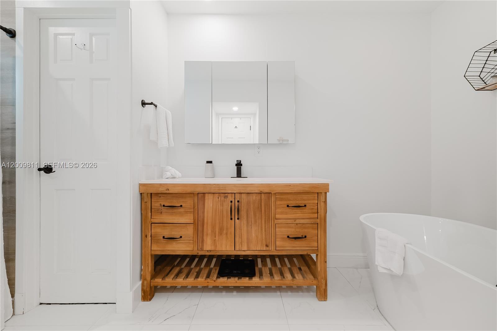 A bathroom features a wooden vanity with a white countertop, a mirror, and a tub — 1106 N 13th Ct, Hollywood FL 33019, HOLLYWOOD, FL