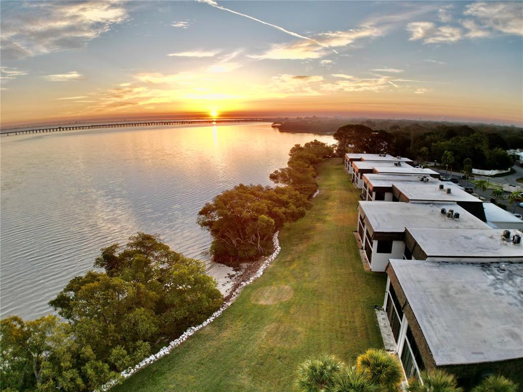 An aerial view of waterfront townhomes at sunset with a long bridge in the distance — 2980 HAINES BAYSHORE ROAD UNIT 124, CLEARWATER, FL