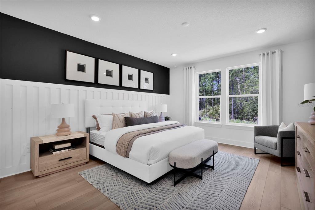 A modern bedroom features a white upholstered bed, black accent wall, and light wood flooring — 308 FISHTAIL PLACE, PALM COAST, FL