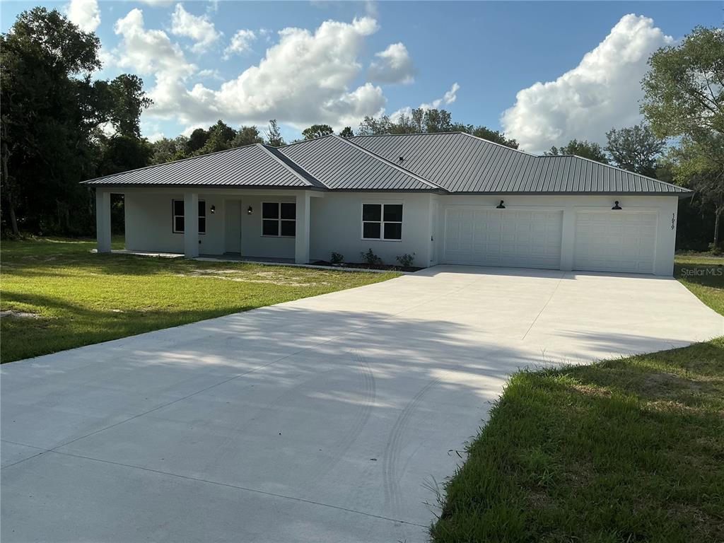 A single-story house with a metal roof, white exterior, and an attached two-car garage — 1619 MAGNOLIA AVENUE, DELAND, FL