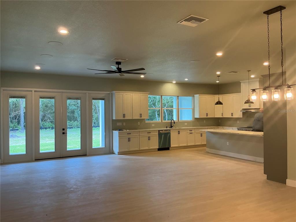A spacious kitchen features white cabinetry, a large island, and glass doors leading outside — 1619 MAGNOLIA AVENUE, DELAND, FL