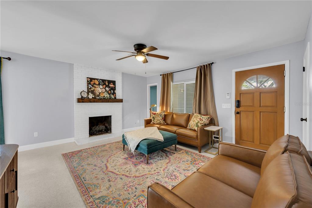 A living room features a white brick fireplace, leather sofas, a patterned rug, and television — 10509 ORANGE GROVE DRIVE, TAMPA, FL