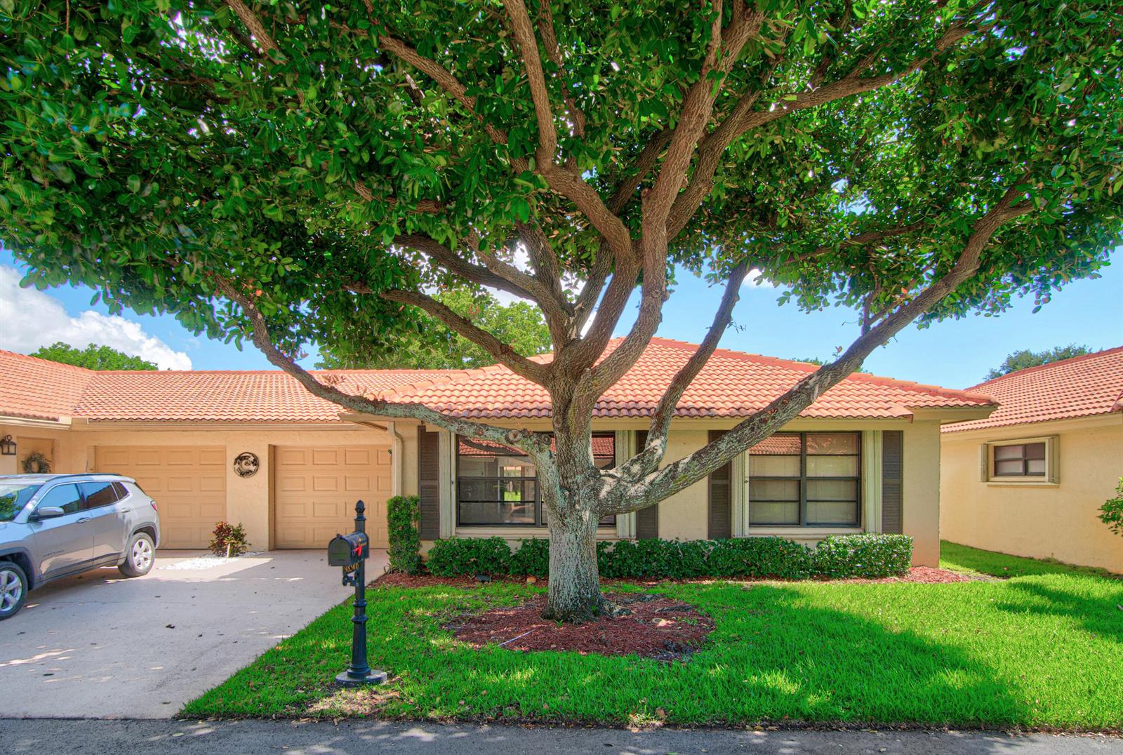 A single-story house with a tile roof, a large tree, and a driveway with a car — 9830 Bischofia Tree Way, Boynton Beach FL 33436, BOYNTON BEACH, FL
