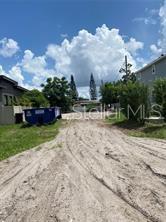 A dirt path leads toward a blue dumpster between two houses under a cloudy sky — 4330 RIXEY STREET, ORLANDO, FL
