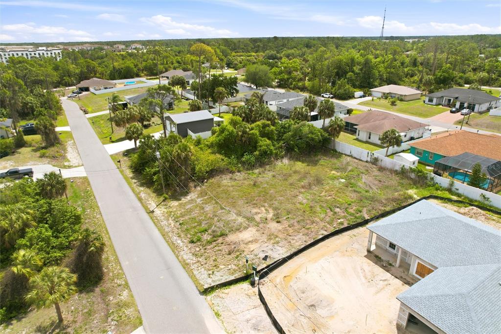 An aerial view shows a vacant, grassy residential lot situated between a road and houses — REMUS AVENUE, NORTH PORT, FL