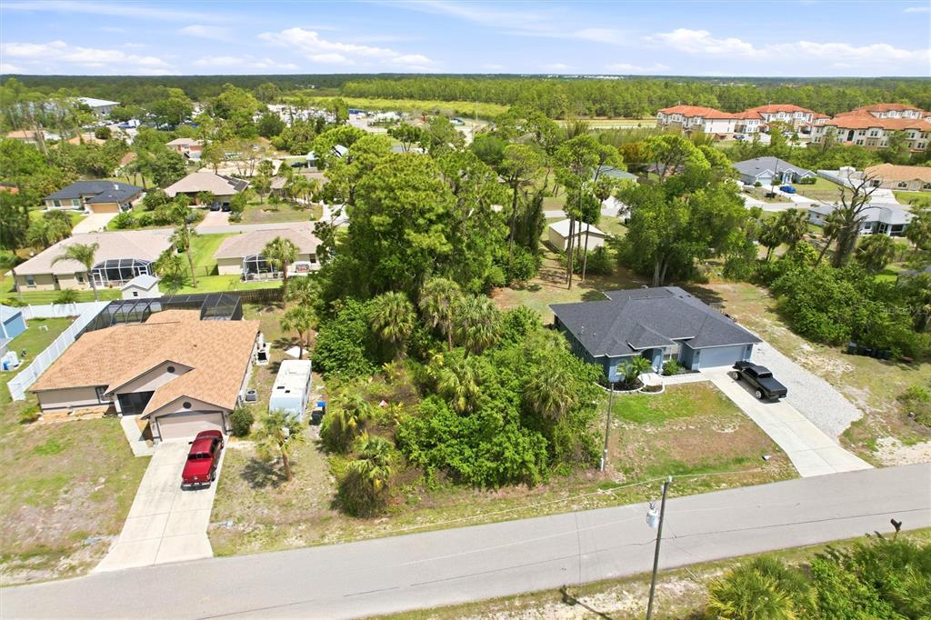 An aerial view shows two houses separated by a wooded lot along a paved road — REMUS AVENUE, NORTH PORT, FL