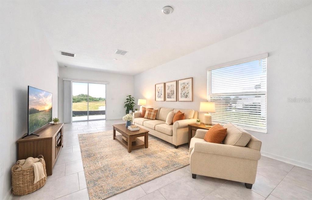 A living room features light tile floors, a beige sofa, an armchair, and sliding glass doors — 573 BELL PRAIRIE CIRCLE, LAKE WALES, FL