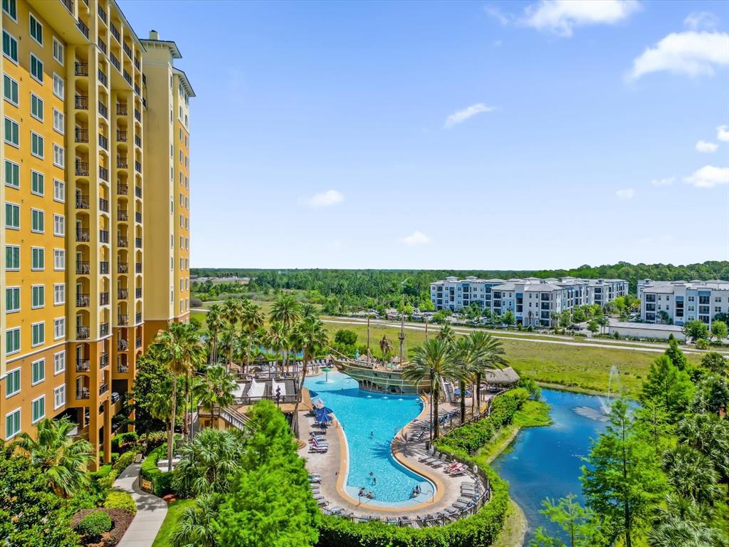 An aerial view of a resort pool with a pirate ship feature and tall buildings — 8101 RESORT VILLAGE DRIVE UNIT 31202, ORLANDO, FL