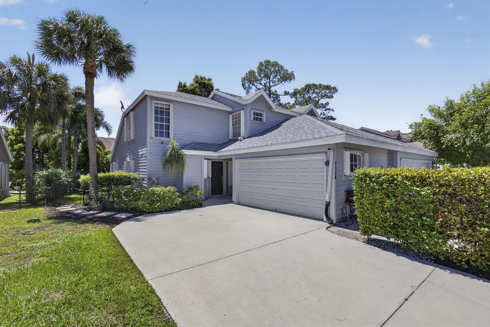 A two-story house with light blue siding, a concrete driveway, and a two-car garage — 936 Honeytree Lane # A, Wellington FL 33414, WELLINGTON, FL