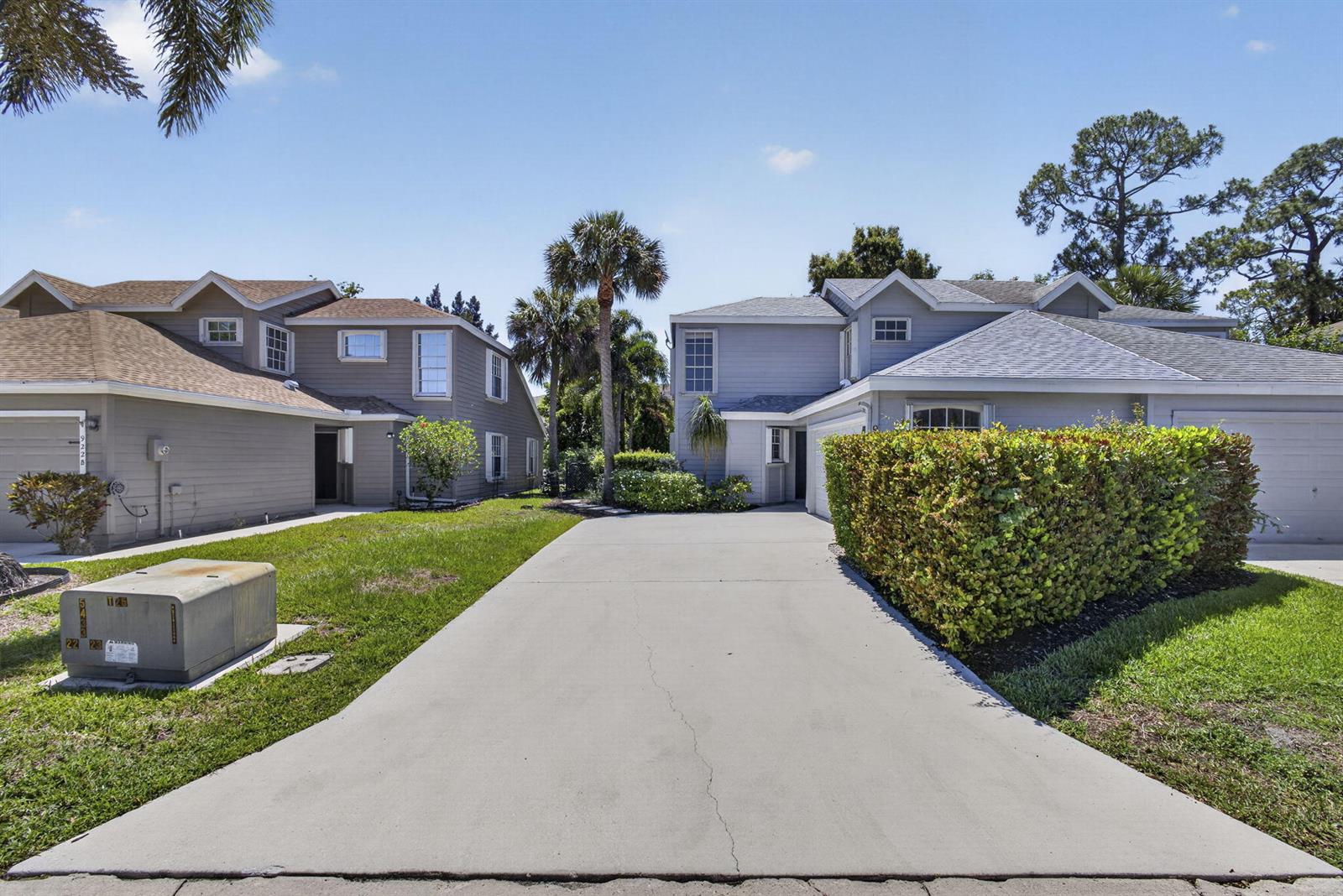 A concrete driveway leads to two adjacent two-story houses with gray siding and green lawns — 936 Honeytree Lane # A, Wellington FL 33414, WELLINGTON, FL