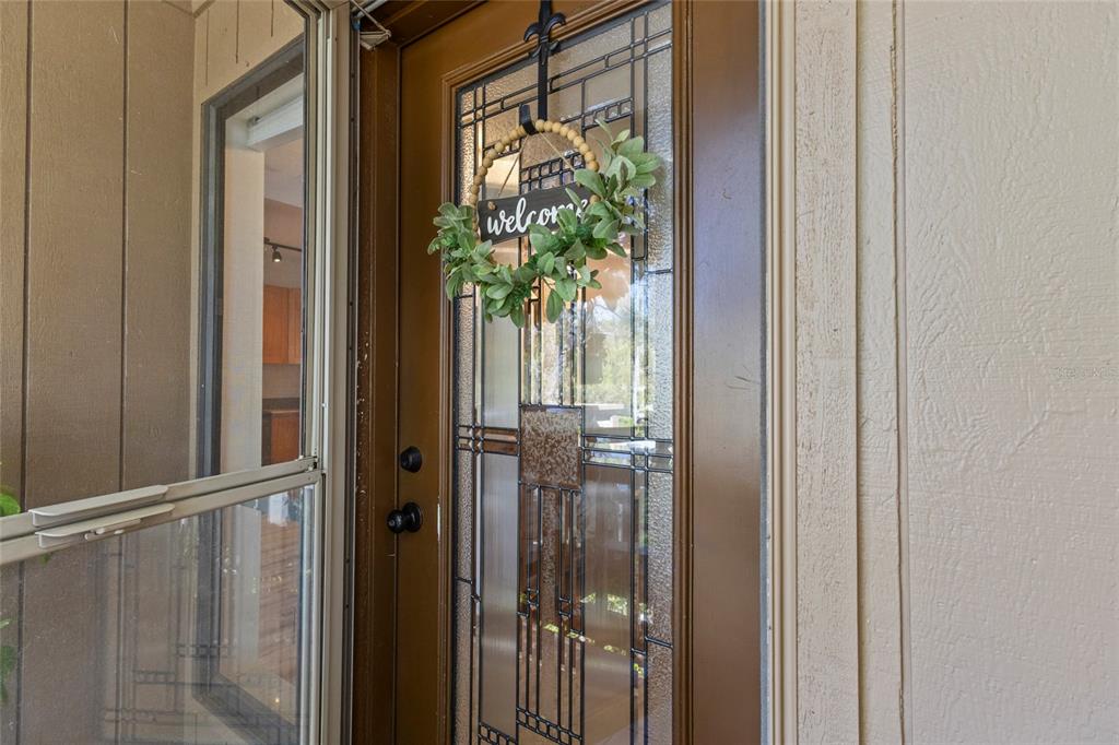 A brown front door with a decorative glass insert and a welcome wreath — 1636 BROOKHOUSE DRIVE UNIT 230, SARASOTA, FL