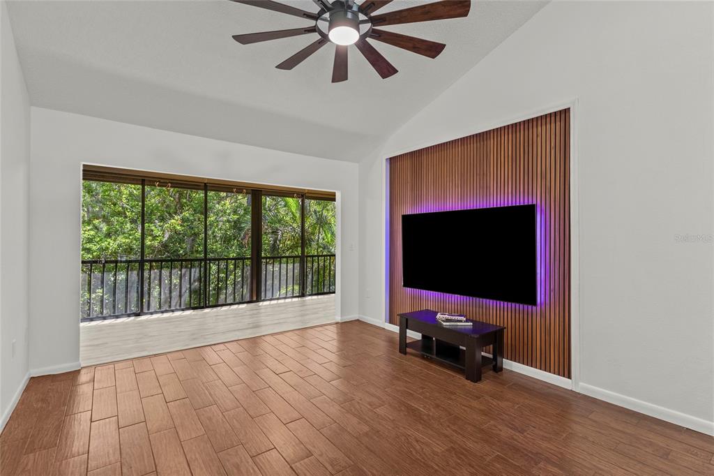 A living room features wood-look tile floors, a slatted wood accent wall, and large windows — 1636 BROOKHOUSE DRIVE UNIT 230, SARASOTA, FL